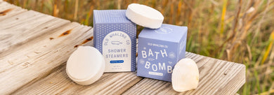 Coastal Calm® Shower Steamer and Bath Bomb on dock with coastal grasses and seashell