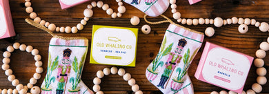 Pink Magnolia boxed bar soaps and green Seaweed boxed bar soaps with bauble holiday nutcracker stockings and wooden garland