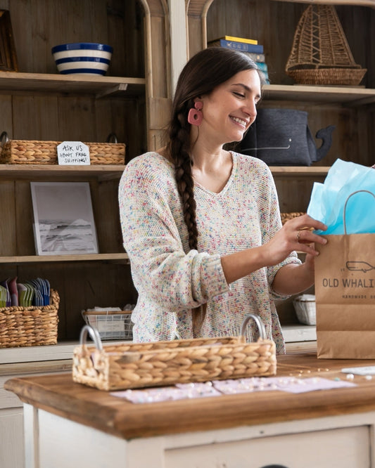 Old Whaling Co. employee filling retail bag with tissue paper inside retail store