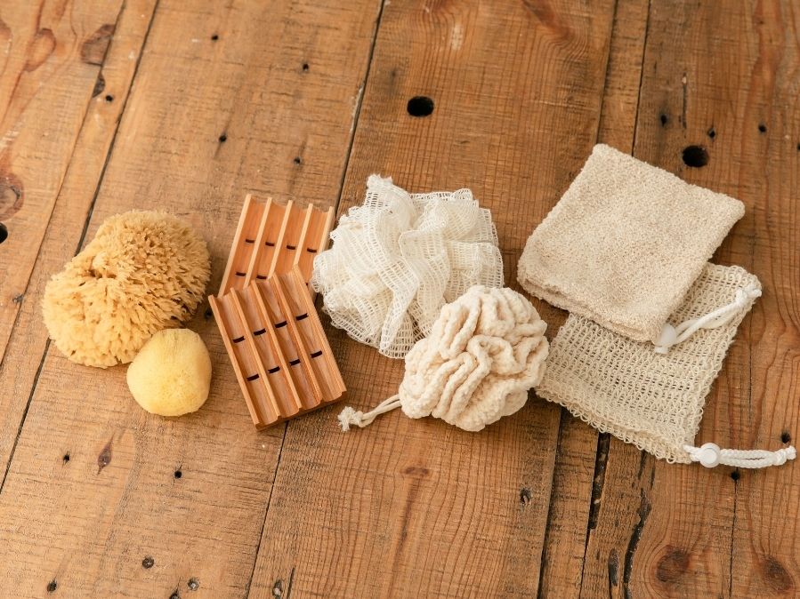 Bath Accessory Flat Lay featuring wooden soap dish, sea sponges, sisal soap pouches