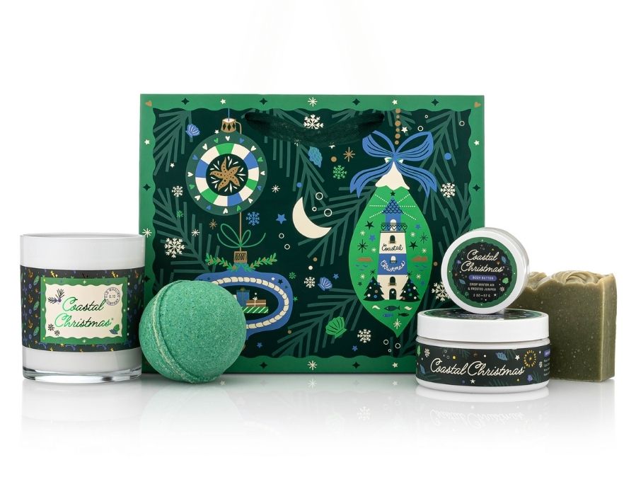 Set of Christmas-themed products including a candle, soap, and decorative gift bag on a white background