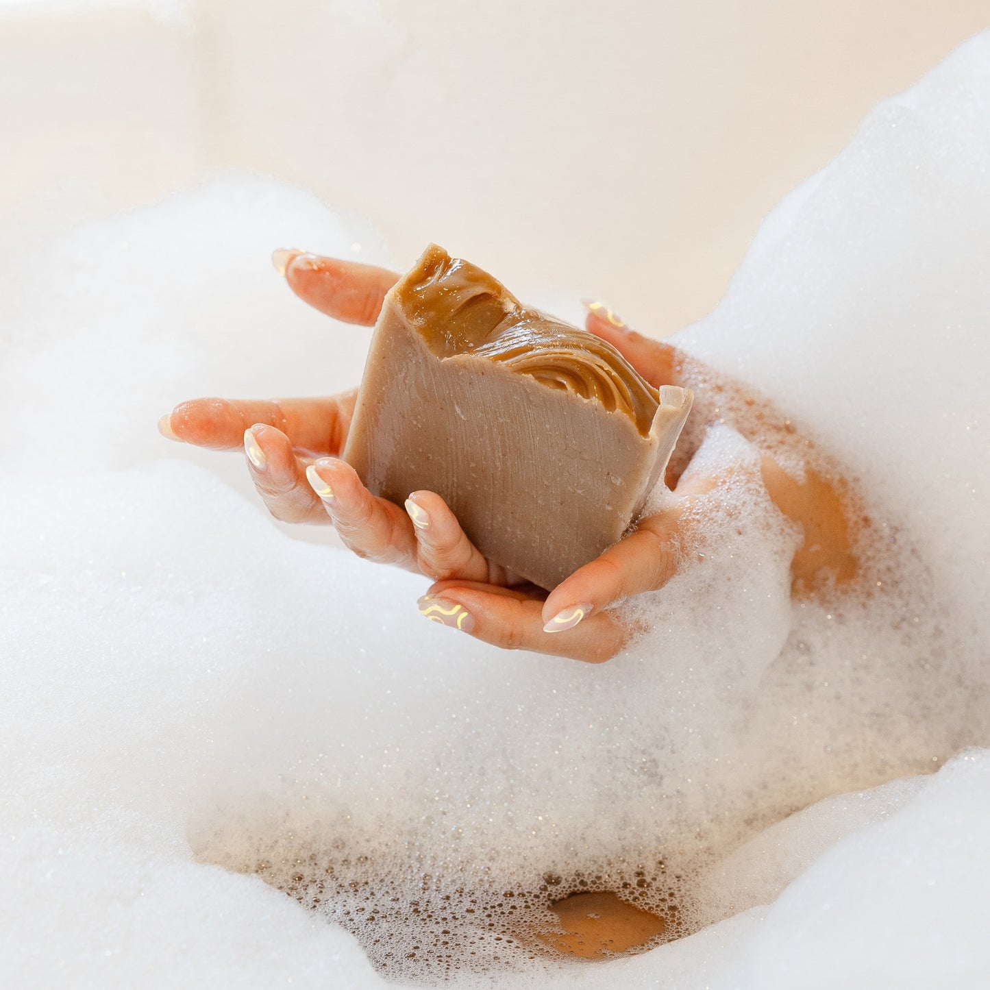 Hands holding Coconut Milk Bar Soap in bubble bath