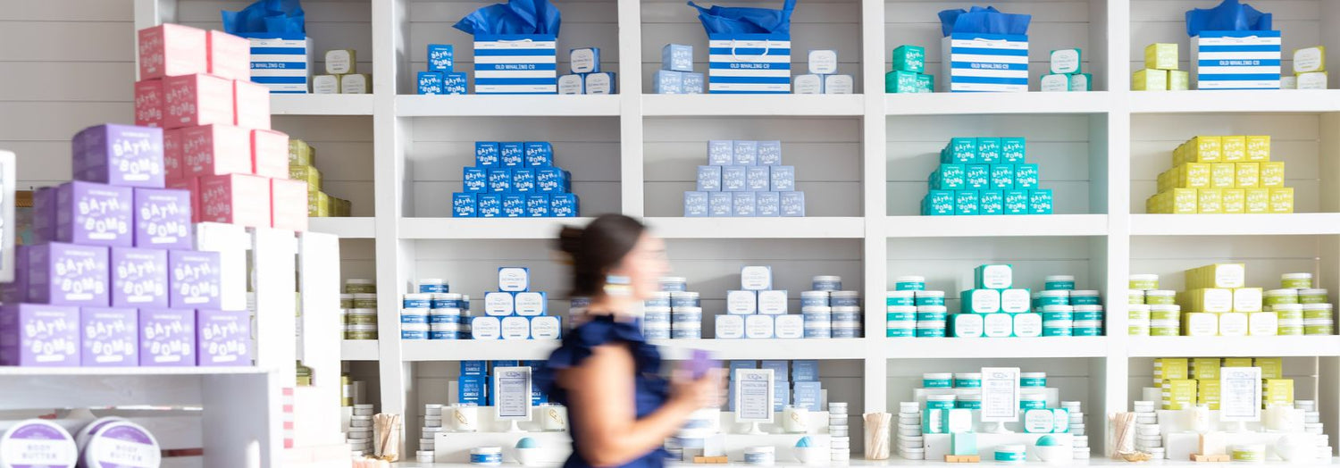 Employee walking past shelves in King Street shops with colorful bath and body items