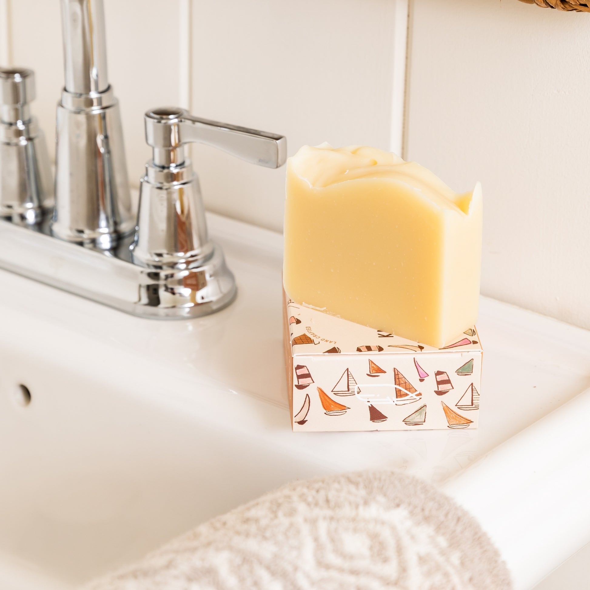 Unboxed Knot Scented Bar Soap sits on top of packaging beside sink