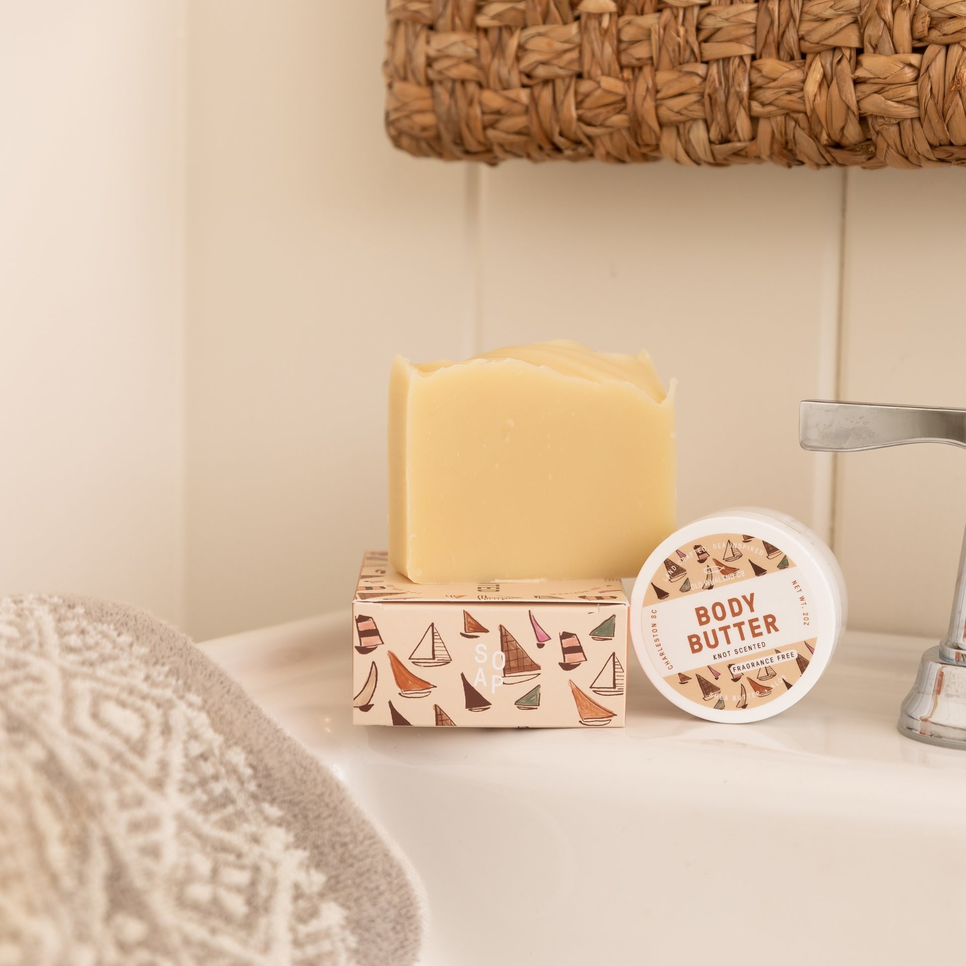 Unboxed Knot Scented Bar Soap styled with packaging and Knot Scented Travel Size Body Butter beside sink