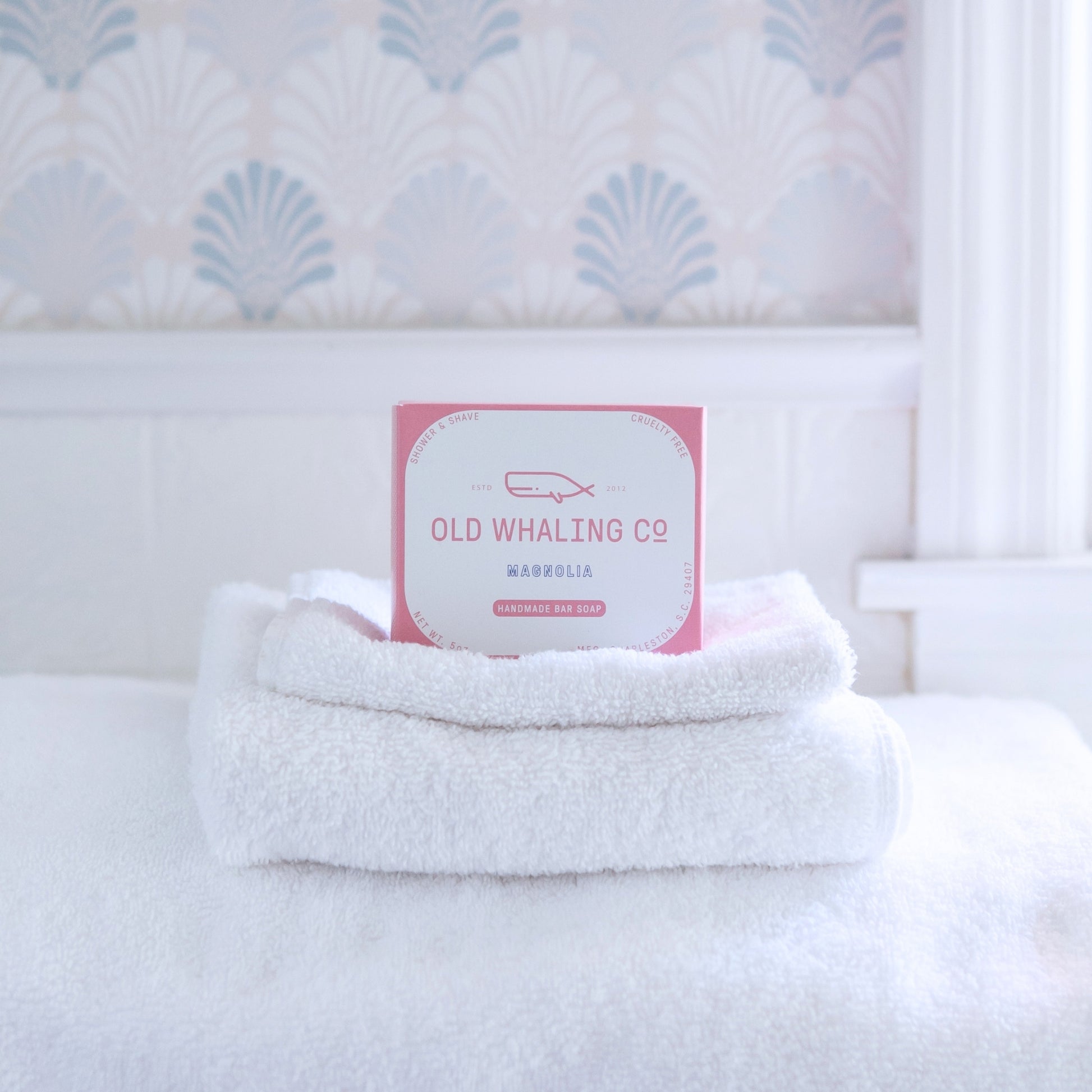 Magnolia Bar Soap box sits on top of white towels in bathroom