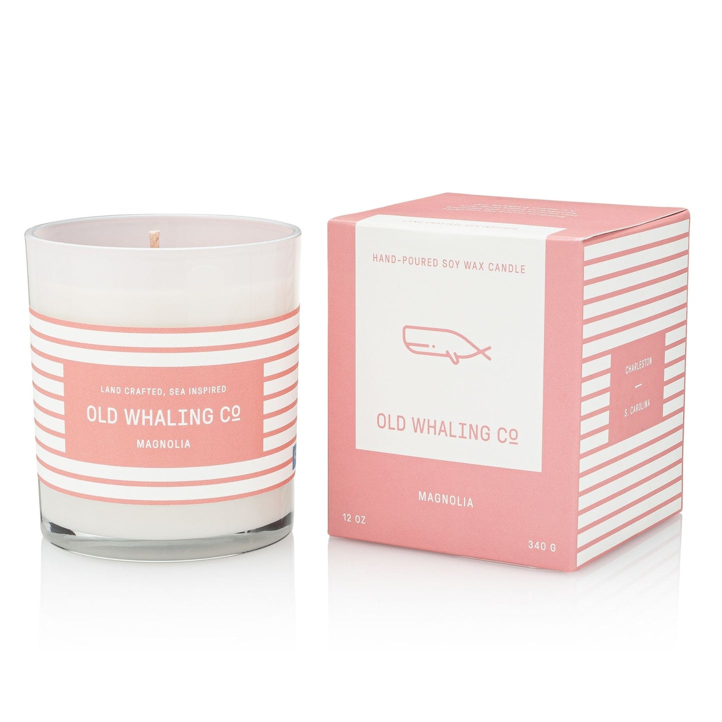 A hand-poured soy wax candle in a clear glass jar with a pink and white striped label, shown next to its matching pink and white striped packaging box. The label reads 'OLD WHALING CO' and 'MAGNOLIA'.
