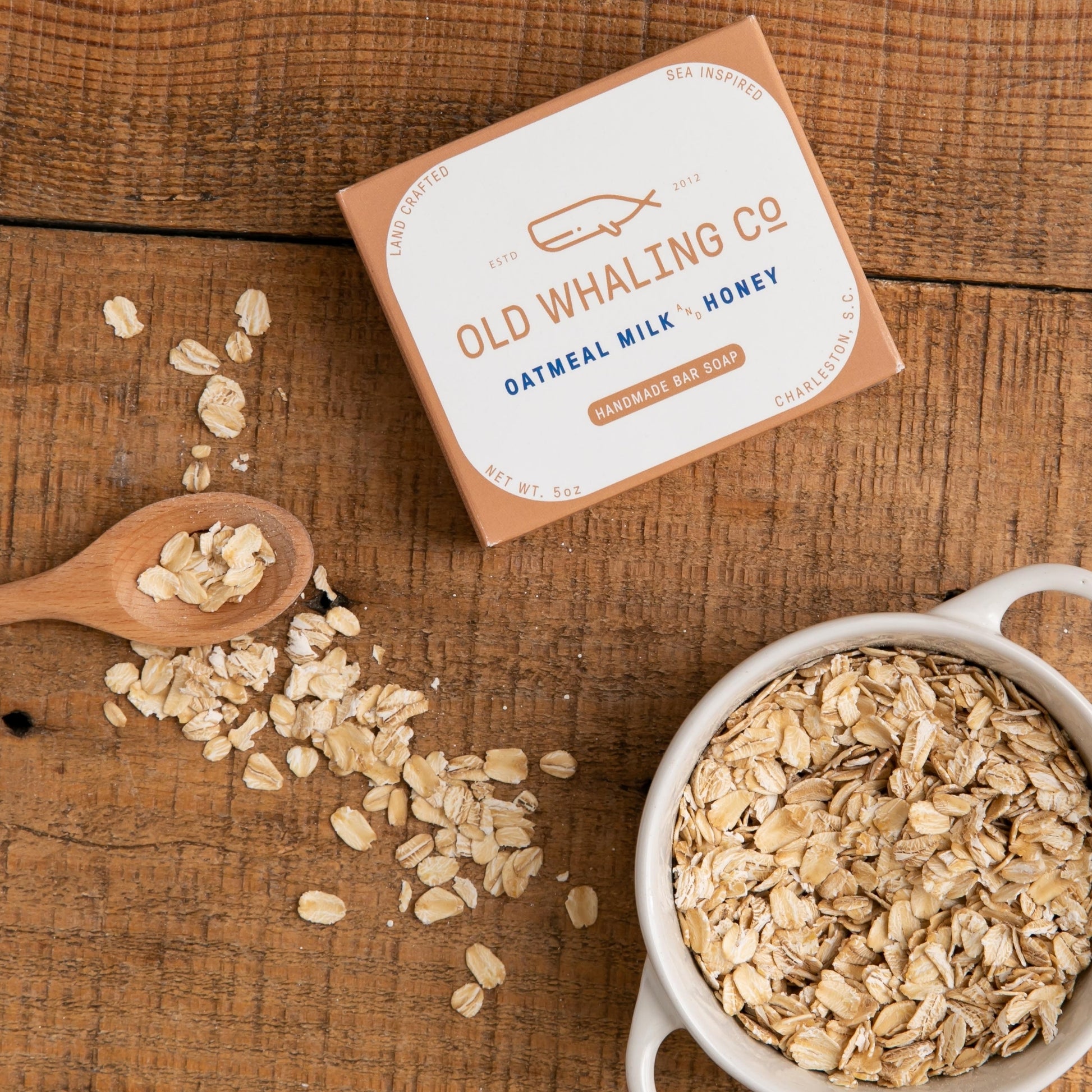 Oatmeal Milk & Honey Bar Soap box styled on wood table beside bowl of oat pieces