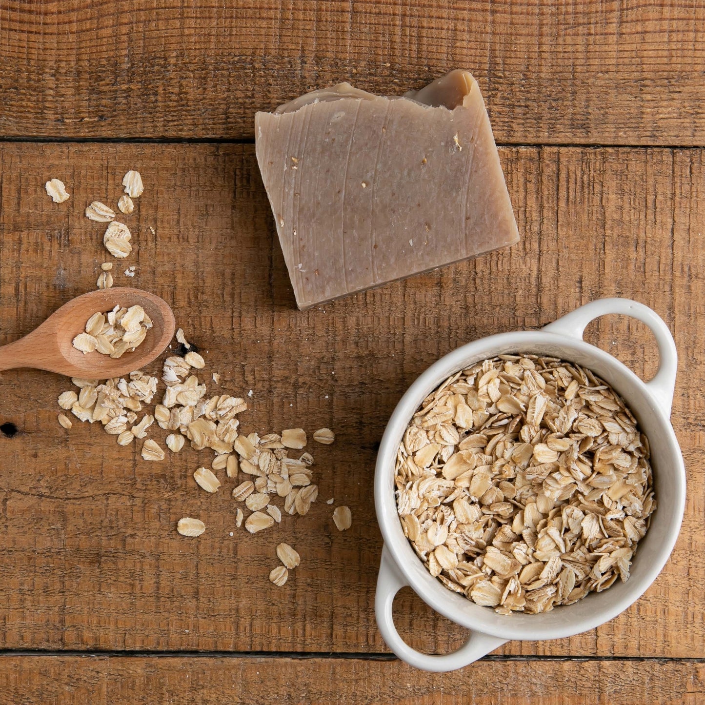Unboxed Oatmeal Milk & Honey Bar Soap styled on wood table beside bowl of oat pieces
