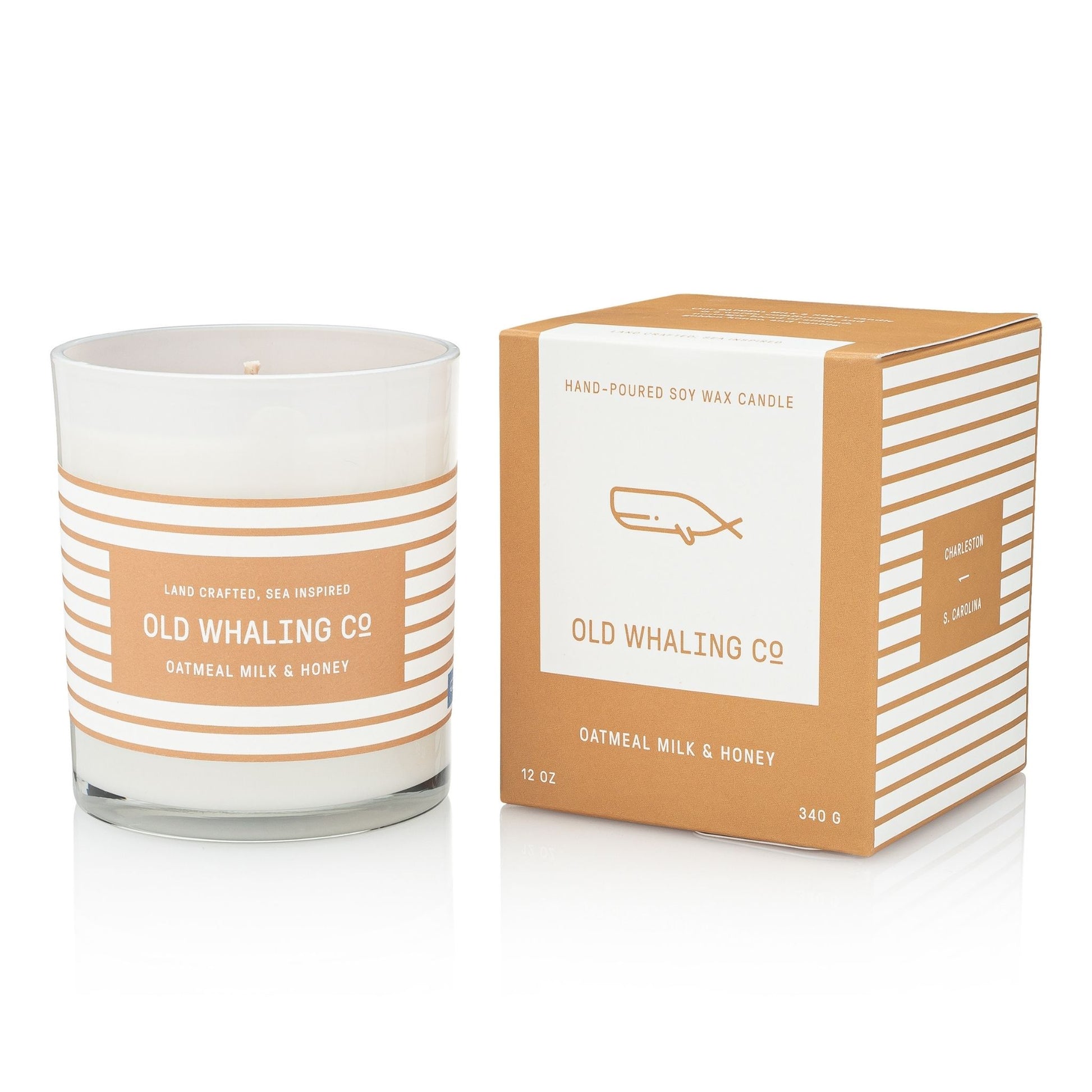 A hand-poured soy wax candle in a clear glass jar with a white label and peach stripes, shown next to its matching kraft paper box. The brand 'Old Whaling Co.
