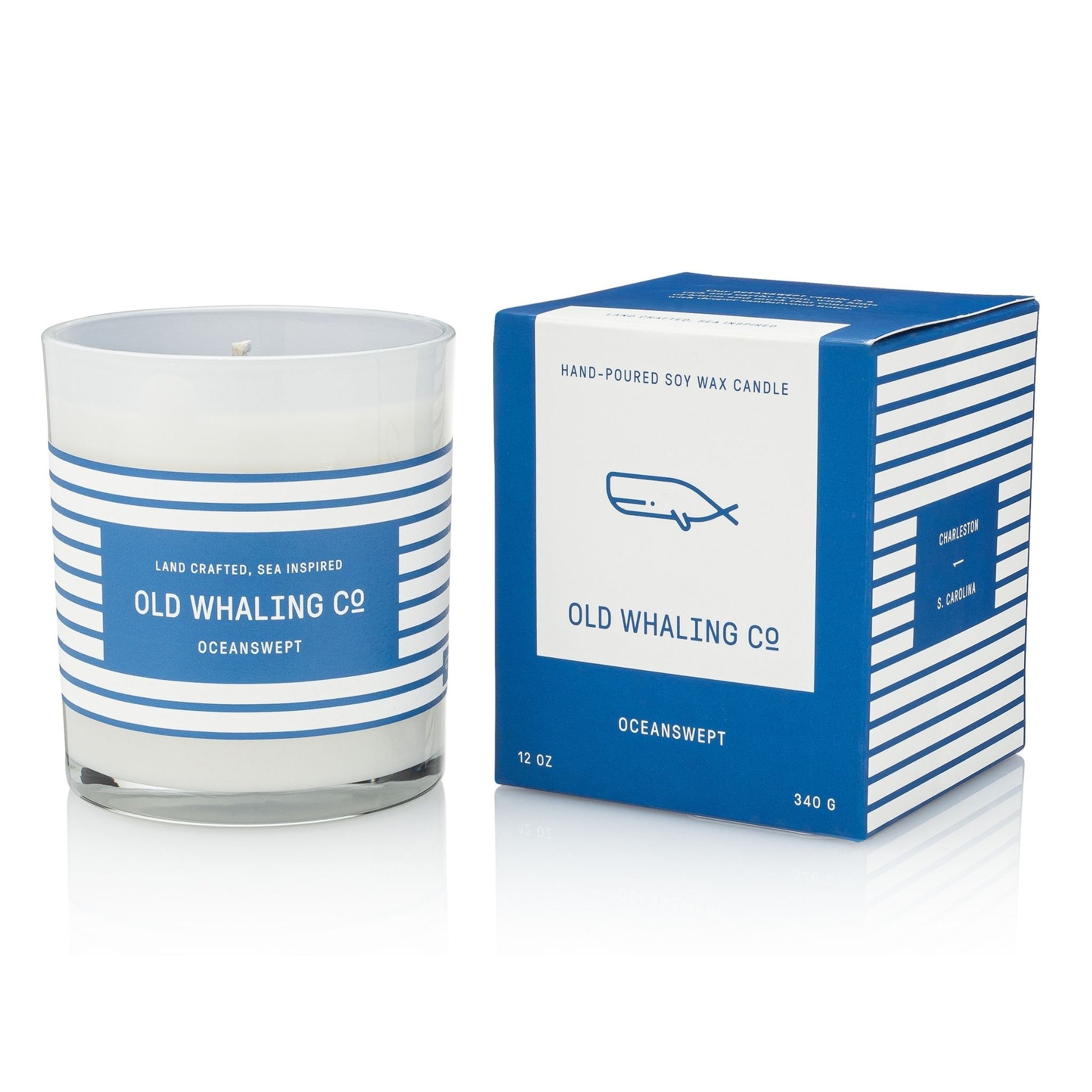 A 12 oz hand-poured soy wax candle in a clear glass jar with a blue and white striped label, shown next to its blue and white striped packaging box. The label reads 'OLD WHALING CO' and 'OCEANSWEPT'.