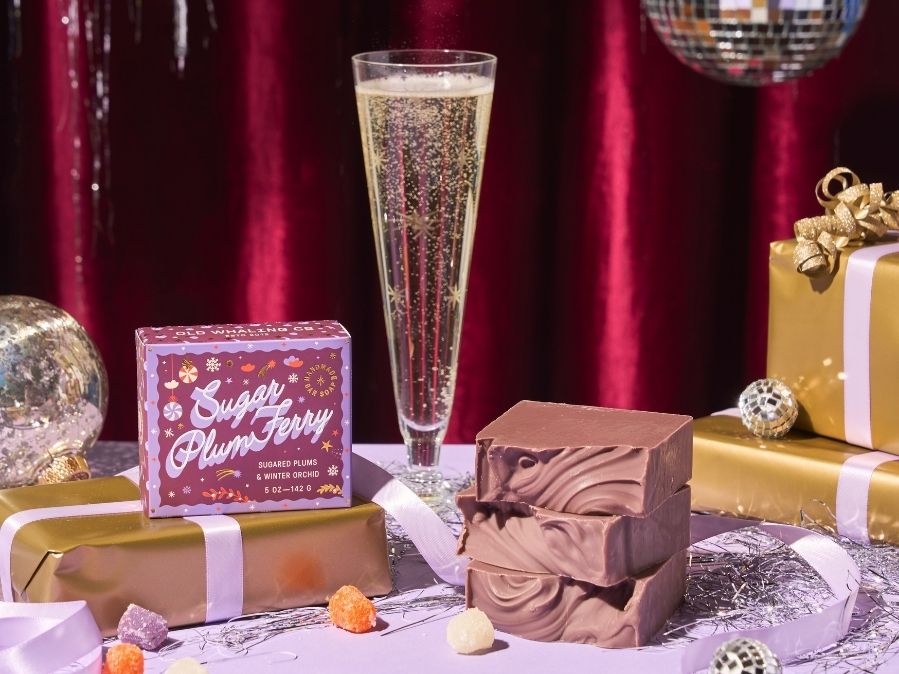 Sugar Plum Ferry bar soaps stylized with champagne flute, disco balls, and purple and gold wrapped gifts.