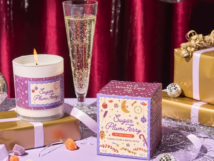 Candle, packaging, and champagne flute on a festive table with red curtain background