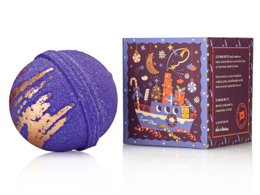 Purple bath bomb with gold accents next to its decorative box on a white background: Sugar Plum Ferry Bath Bomb Illustration by Lulu Dubreil Old Whaling Co
