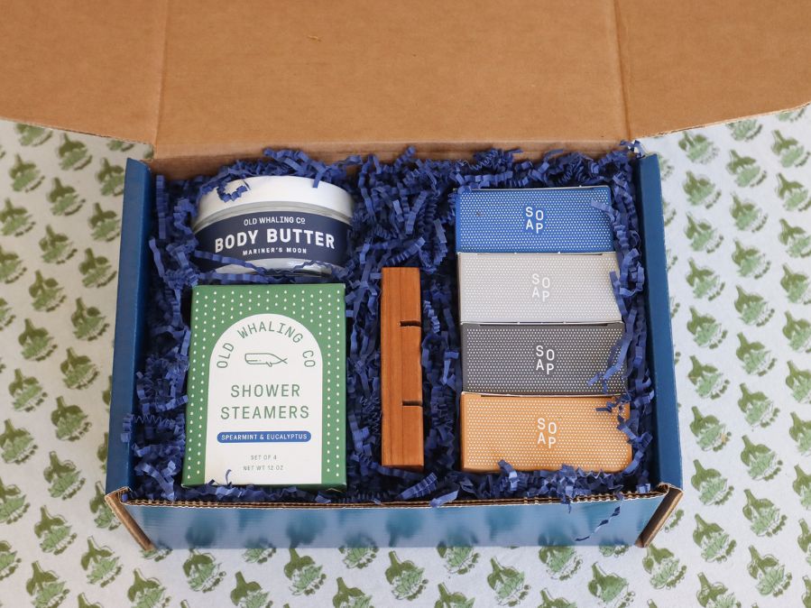 The Dad Gift Box complete with Old Whaling Company products sitting on a table cloth with green floral patterns