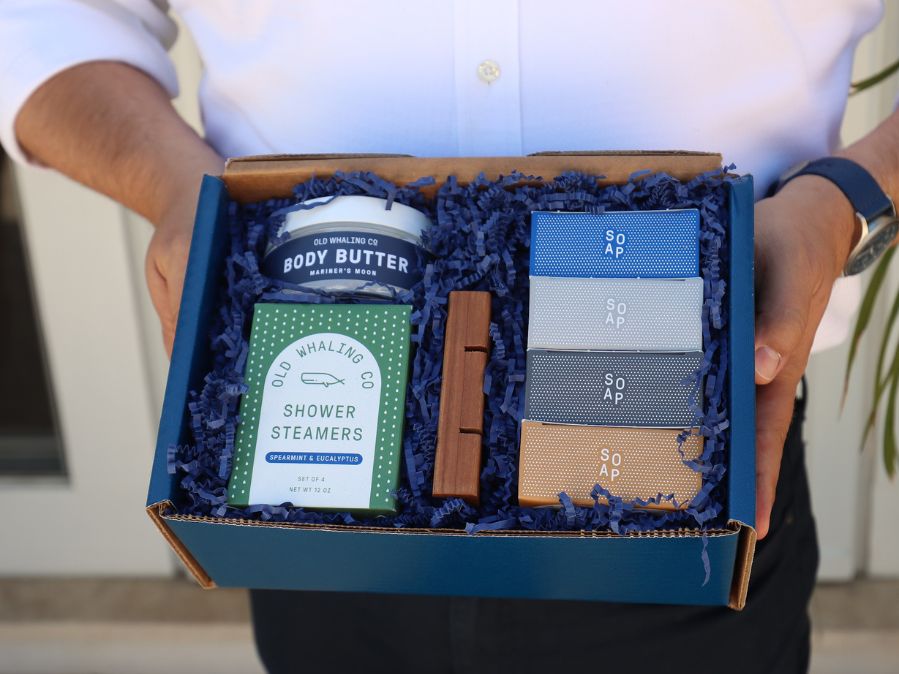 Man with watch wearing white button down shirt holding Dad Box with Old Whaling Company products