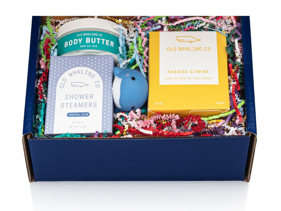 Old Whaling Gift box complete with candle, shower steamers, body butter and a cute whale bath toy in side blue box with rainbow crinkle paper 