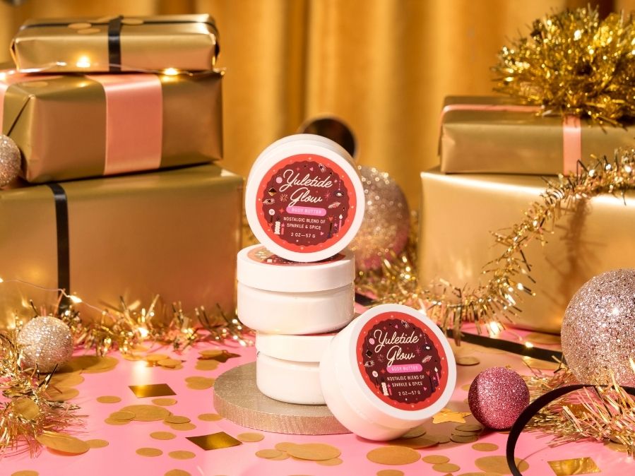 White containers with pink labels on a festive background with gold presents and decorations.