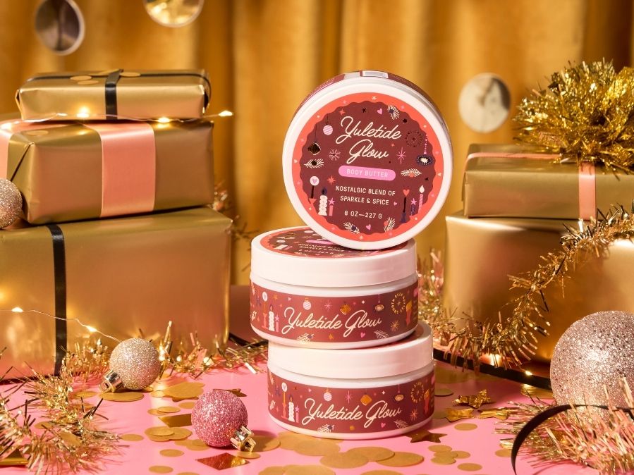 Body Butters labeled 'Yuletide Glow' on a festive background with gold presents and decorations.