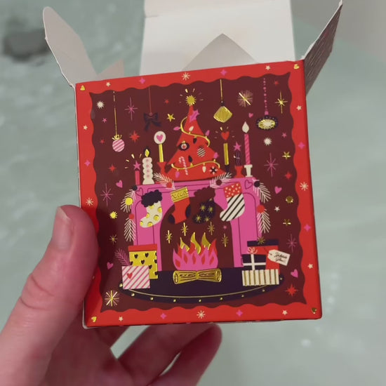 holiday bath bomb Yuletide Glow being put into bath water showing the fizz