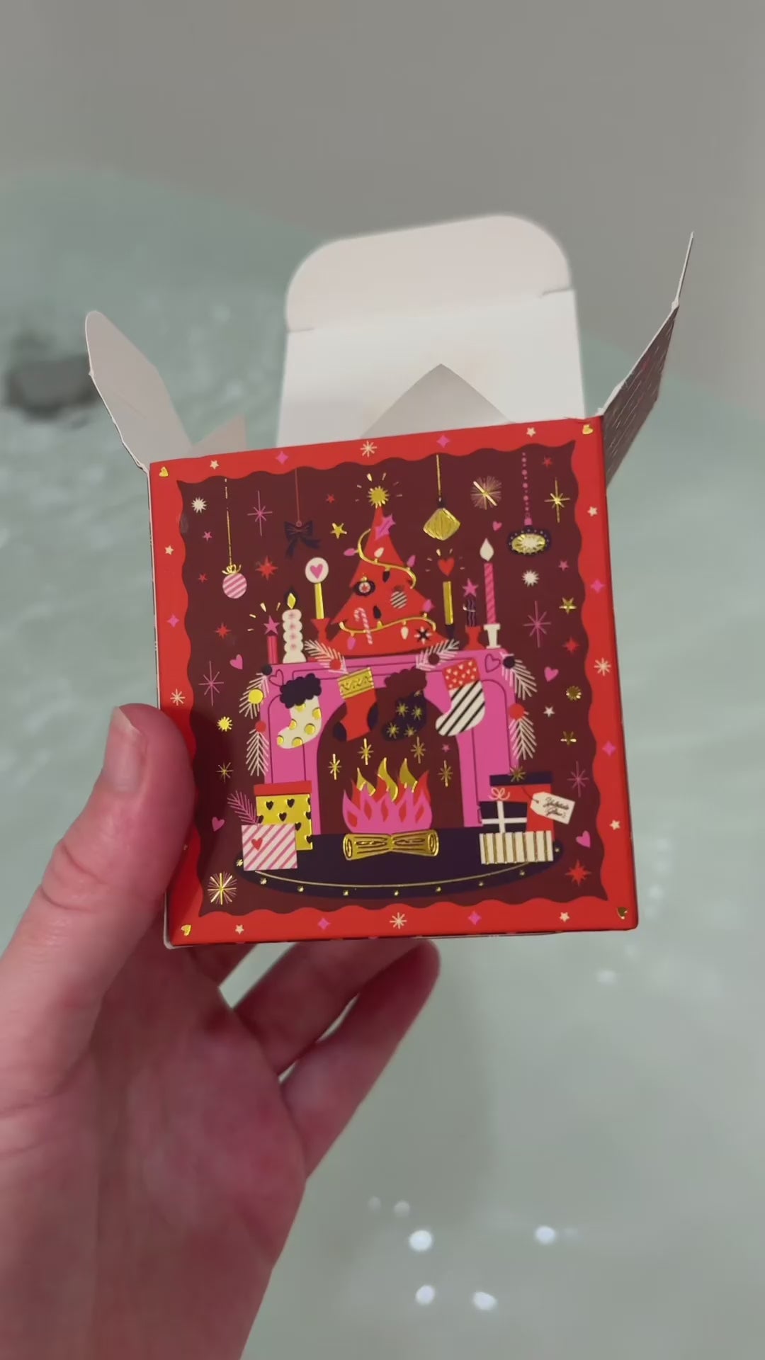 holiday bath bomb Yuletide Glow being put into bath water showing the fizz